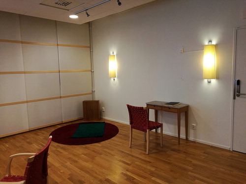 FIG 8 The right-side of the room of silence, with the Muslim prayer corner and the low wooden table with the guest book for thoughts and prayers in 2017. Photograph: Anna Petersson.