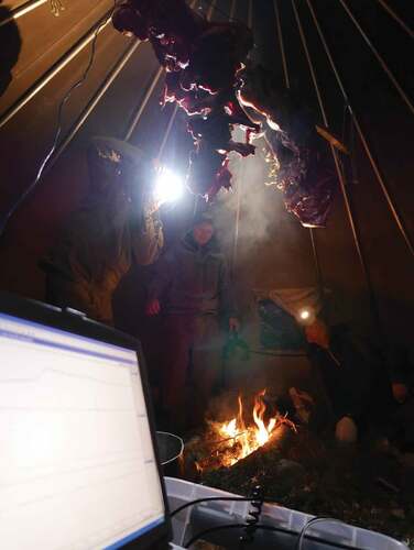 Figure 2. Scientists and reindeer herders research together in the lávvu-laboratory. The data-collection included glow and smoke temperature measurements, smoked reindeer cut samples for PAH-analyses, photo-documentation, dialogues, common observa-tions, and sensation of the smoking practice.