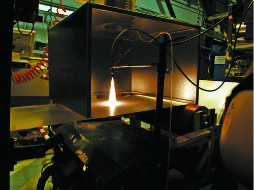 FIG. 1 Photograph of the practical situation for LFS nanocoating the roll-to-roll paperboard. The distance from burner face to paperboard is 15 cm.