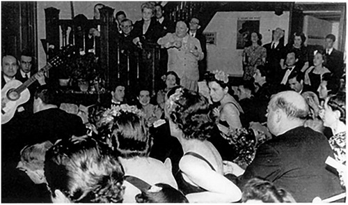 Figure 3 Flamenco party at the British Institute in Madrid (1941 or 1943). Walter Starkie and his wife, stand at the foot of the staircase. A poster of Winston Churchill hangs on the right, next to the library signpost. Photograph reproduced courtesy of Mr John Murray.