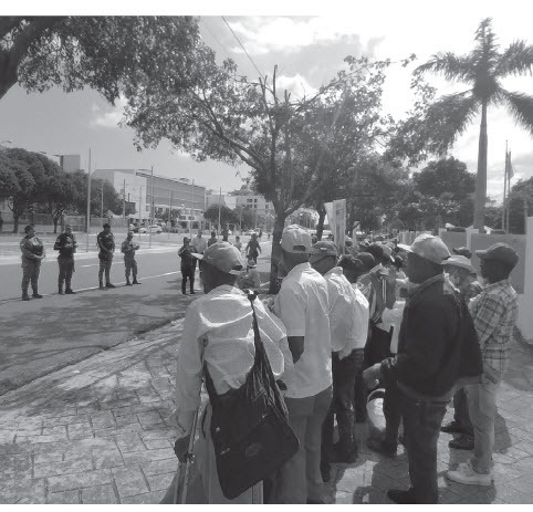 Retired cane workers face a line of police outside the Ministry of Labor in Santo Domingo, December 7, 2022. (SIMÓN RODRÍGUEZ)