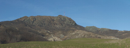 Figure 1. The landscape view of Mt. Prinzera's eastern side. The ophiolitic rock complex rises from the surrounding gentler slopes made up of soft rocks (clay-rich breccias and flysch). The rock mass is divided into several portions (in the middle/left-hand side of the photograph the principal one and on the right-hand side the secondary blocks) because of the presence of E-W fault system.