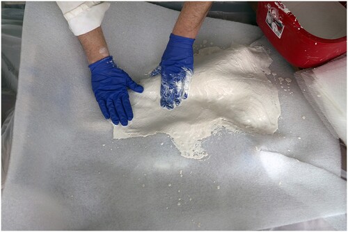 FIGURE 11. The first layers of plaster and fiberglass being applied to the darted liner resting on the specimen.