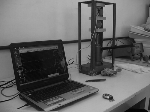 FIGURE 1 Equipment for compression application, formed by a hydraulic jack, two acrylic plates, and an instrumented sphere connected to a computer (a), detail of a treatment application on an orange (b).