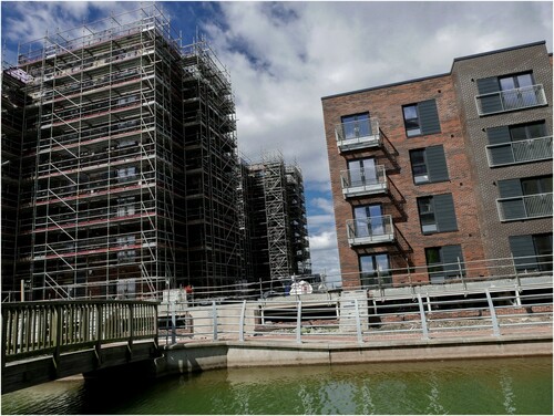 Figure 8: Construction continues apace on these council houses (for ‘Mid-Market Rent’, which equates to 80% of market rent). The bridge was designed to lead to a luxury property development and has been fenced off for over a decade. The shallow water channel is constructed on reclaimed land above what was once a working dock, a neat illustration of ‘the recuperation of history […] simply reproduced as pastiche’ (Harvey Citation1990, 82). Source: author 2020.