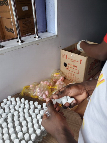 Figure 5. Peer educators prepare small bottles of sanitiser to give to members and sell to the general public.