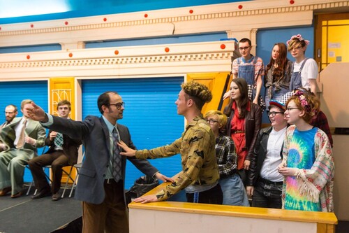 Figure 3. Michael Justice as Allan Horsfall (left) faces Christopher Brown as Andrew Lumsden (right) with members of the Burnley Youth Theatre. Photo credit: Nicolas Chinardet.