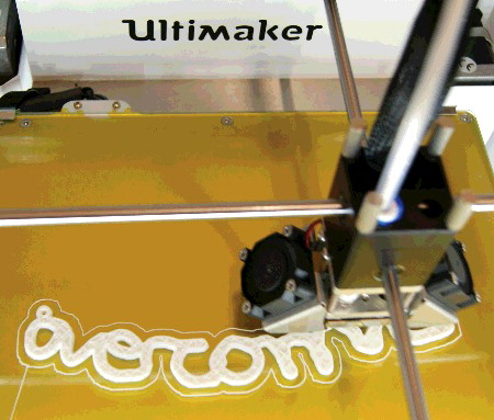 Figure 3. The pipe-cleaner lettering emerges from the 3-D printer. Note the addition—visible on the left-hand side—of mounting holes to allow the text to hang from a thread or chain.