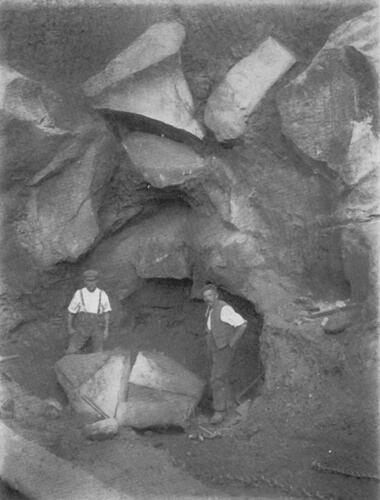 FIG. 4 Two sarsen-cutters standing either side of a partially cut boulder in the bottom of a pit at Bristow’s Stone and Brickyard, early 20th century. This is not the pit observed by Spicer (Citation1905), but is on the same site which he visited (source: The Geologists’ Association).