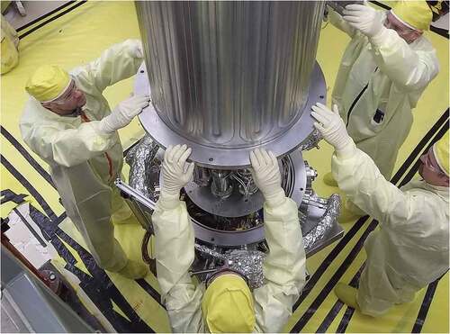 Fig. 9. LANL and NASA engineers lowering the top of the vacuum chamber over the Stirling engines.