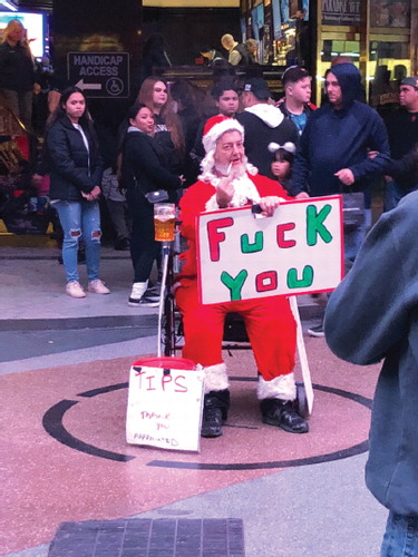 Bad Santa turns his sign around to reveal his profane nature.