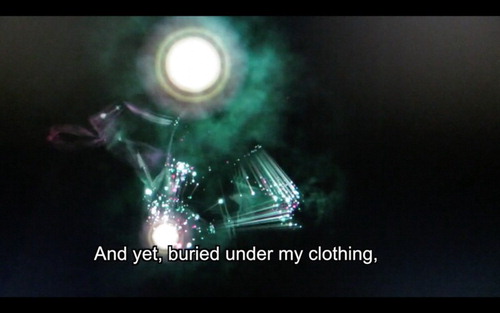 Figure 7. Still frame of multi-coloured bursts of light against a black background, with a caption reading ‘And yet, buried under my clothing’, describing inner biopedagogies used to maintain self-starvation. From Litany of White Noise by Jen Rinaldi.