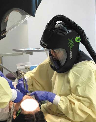 Figure 6. Medical personnel working on patients with highly infectious diseases wear a powered air-purifying respirator (PAPR). In this image, Dr. Arleen Azar of Los Angeles, California, prepares to perform AGDP wearing one
