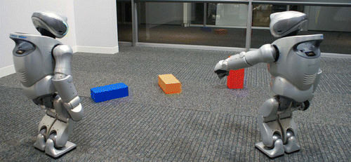 Figure 1. Sony QRIO humanoid robots play a language game about physical objects in a shared scene.