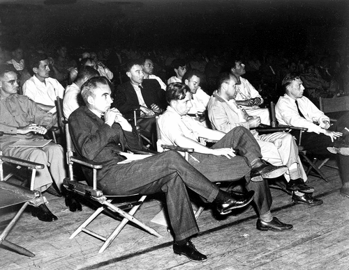 Fig. 3. A conference at Los Alamos, August 1946. Left to right: The man in uniform, leftmost, is Oliver Haywood. Over his left shoulder is Norman Ramsey. Although we can only see a forehead and some glasses, next to Ramsey is Gregory Breit. Bradbury is up front; next, we have Oppenheimer. Behind Oppenheimer is, perhaps, Herb Lehr. Back on the front row, next to Bradbury, we have John Manley. Over Manley’s shoulder is Feynman. Back to the front row is Fermi. Over Fermi’s shoulder, apparently seated to Feynman’s left, is James Tuck. On the front row all the way over to the right is Jerry Kellogg. According to the inventory, Arthur Schelberg is in the image as well—very likely the half-face behind Feynman. Los Alamos records have this photograph taken around August 1946. The speaker was Philip Morrison; see Appendix C. (Credit: Alan Carr).