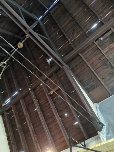 Figure 3. A view up at the ceiling during initial emergency renovations showing steel reinforcement brackets and lateral tie rods that were added for structural stability, and also showing sunlight shining through cracks and holes in the roof of the church. Photograph by Gabriel Cira.