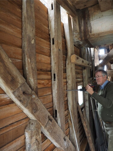 Figure 17. Two pre-used old timbers that were upcycled during a past rebuild into wall studs in the buck wall at Great Chishill Windmill. Martin Bridge is drilling a dendro sample from one of them, which when analysed showed it was from a tree felled in the period 1693–1726 (photo: Martin Davies)
