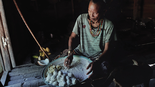 Figure 7. A woman prepares taro dumpling rolled in grated coconut (subbet).