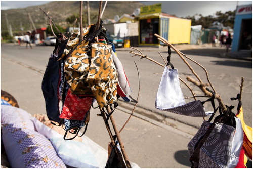 Figure 5: Face masks on sticks for sale by the side of the road in Masiphumelele informal settlement, Cape Town. Wearing face masks in public is compulsory in South Africa; failure to do so can be punishable by imprisonment of up to six months. Image credit: Samantha Reinders.