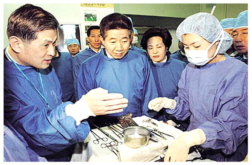 Fig. 4 President Roh Moo-hyun (center) visiting Hwang's lab (December 10, 2003). Roh was so deeply impressed by Hwang's presentation (he used the word “electrified”) that he promised firm support to Hwang's future research, while the questions about ethical issues already were raised then
