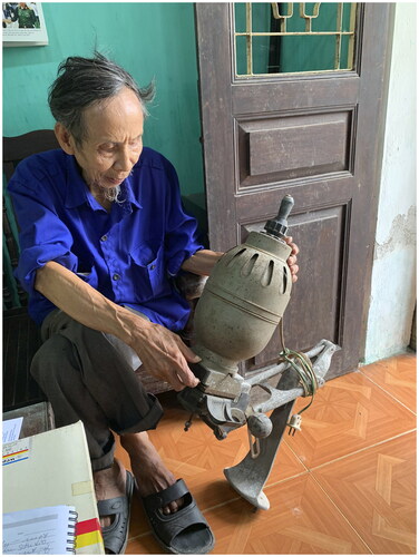 Figure 7 Mr. Nguyễn Văn Thực examines the enlarger he used for many years in a joint venture workshop. (Photo by Laurel Kendall)