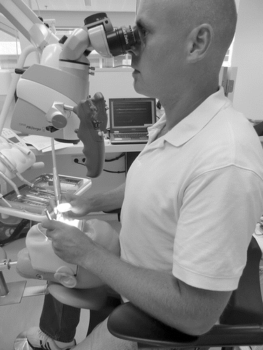 FIGURE 1 An endodontist working in a dental unit on a phantom head using a microscope.
