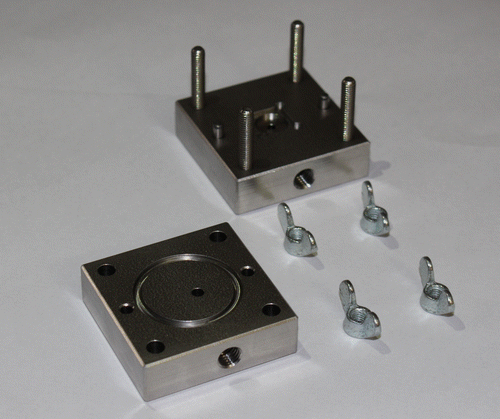 Figure 9. Photo of the two parts that compose the sample holder with its oring grooves, sample cavity and wing nuts screws.