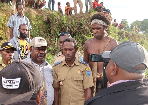 Figure 6. Regent of Agats (centre left) facing his videographer for an interview with the village head (centre), on departure from Mabül village, December 2017. Bolumale looks on in traditional dress, without understanding the Indonesian talk.