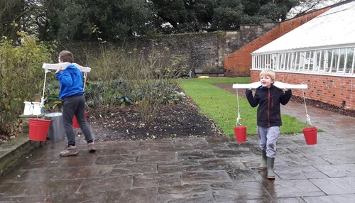Figure 1. Two children learning about carrying water: weight, movement, balance, etc. at Dyffryn Gardens, NT Wales.