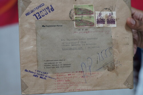 Figure 14 Envelope of a registered parcel sent by Deutsche Welle to Rajendra Swarnkar. On the top right corner the collector has noted the date of its arrival (15.04.1991) and that it was 44 days after his father’s death. At the bottom the collector lists the contents of the parcel. Private Collections Rajendra Kumar Swarnkar, Photo: Bikaner, April 2, 2022, Jyothidas KV ©Bajpai.
