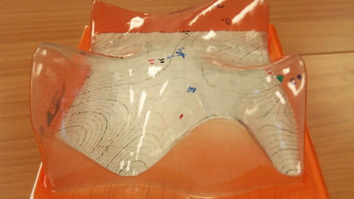 Figure 1. One of the transparent plastic surface models developed by Aaron Wangberg at Winona State University as part of the Surfaces project. Each of the six color-coded surfaces is dry-erasable, as are the matching contour maps, one of which is visible underneath the surface. For further details, see [Citation49, Citation50].