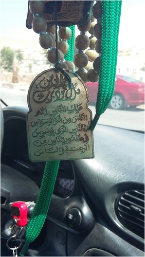 Figure 5. Prayer beads (masbiha) and a plaque bearing Surat-an-nas (the final book of the Quran) hang from a car’s rear-view mirror. Electronic counters like the one on the turn signal have increasingly become an alternative to prayer beads, allowing users to better track of their daily prayer totals.
