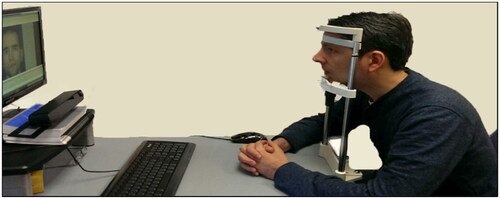 Figure 5. Our ET setup: viewing the subject’s face seated on a chin rest, and the near-infrared ET device aiming at the subject’s eyes as he observes the monitor. The ET detects movements of less than half a degree of visual angle.