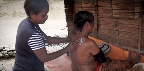 Figure 5. Palmira massages a patient with a candlenut paste. Still from Holding Tightly.