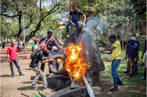 Figure 1. Protesters poking a fire at the feet of the statue of State President C R Swart on the Bloemfontein campus of the University of the Free State, Bloemfontein, South Africa, on 22 February 2016. GALLO IMAGES/MEDIA 24. Reproduced with permission.
