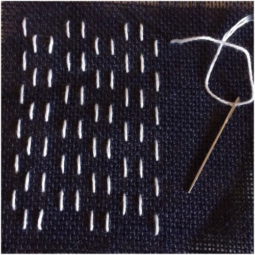 Figure 4. Starting to decorate a small square coaster with hitomezashi. The first 10 vertical lines of running stitch have been completed.