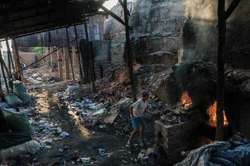 Figure 4. A brick worker stokes the kiln fire with garment waste (Photo by Thomas Cristofoletti; copyright RHUL).