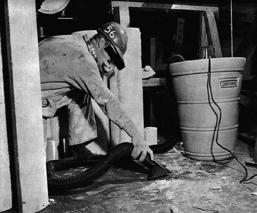 Figure 8.  Worker cleaning work area with a vacuum, while wearing a respirator. Photo source: Carl Mangold. Previously published in Hollins et al., Citation2009.