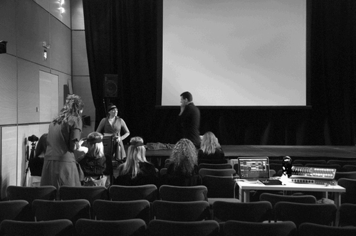 Figure 2. The live visuals and BCI performer (first author) preparing two audience participants prior to the performance at CCA: Centre for Contemporary Arts Glasgow, 30–31 July 2015. ©2015 The authors and Catherine M. Weir.