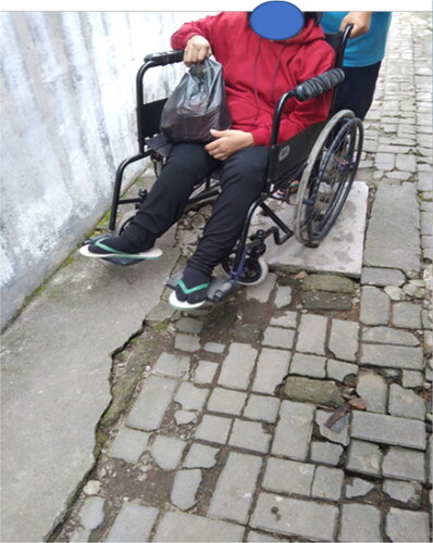 Photo 1. Participant 6 was helped by her carer to move her wheelchair when passing a block paved road to go to a grocery store. The paving blocks were poorly installed. They popped up, making the road surface bumpy and restricting wheelchair’s movement.